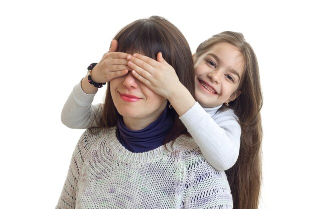 Menina alegre esconde os olhos da mãe e sorrisos isolados no fundo branco