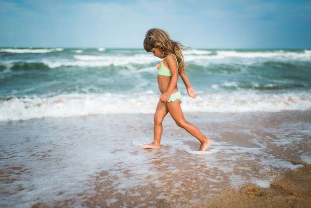 Menina alegre gosta de um dia de praia enquanto relaxa no mar em um dia ensolarado de verão quente. Férias de verão e conceito de relaxamento