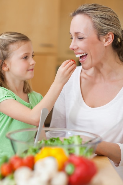 Menina alimentando sua mãe com salada