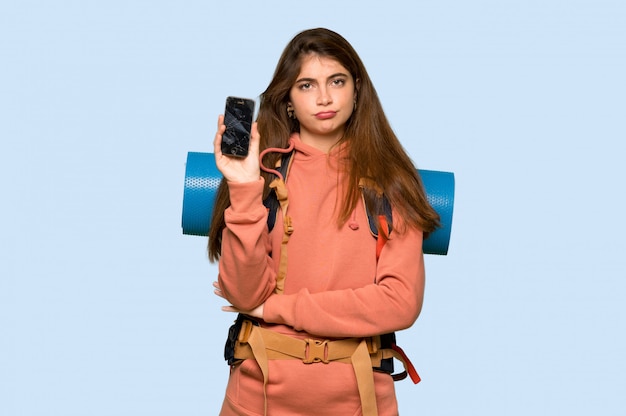 Menina alpinista com um telefone quebrado no azul