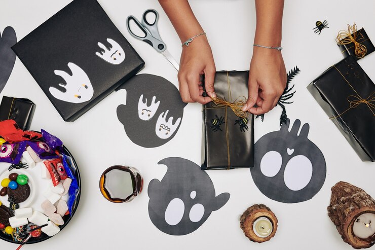 Foto menina amarrando o laço no presente de halloween embrulhado em papel preto, vista de cima
