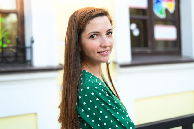 Menina anda pela cidade em um vestido verde de bolinhas