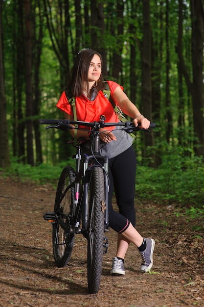 Menina andando de bicicleta na floresta