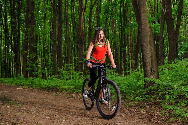 Menina andando de bicicleta na floresta