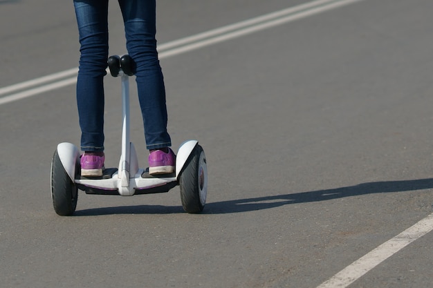 Menina andando de giroscópio em uma estrada para pedestres, copie o espaço