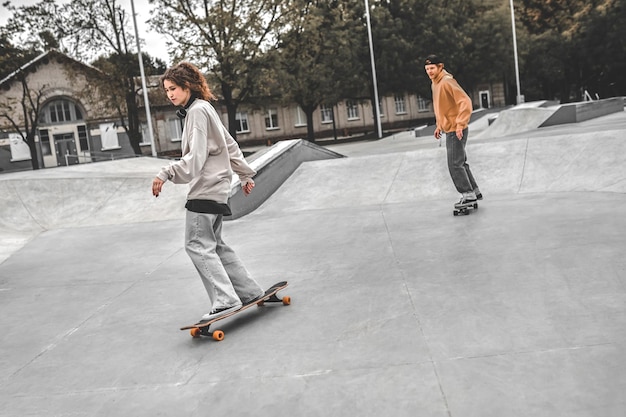 Menina andando de skate na frente e cara atrás