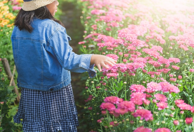 Menina andando e toque na flor de crisântemo