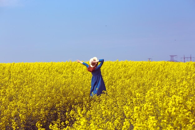 Menina andando em um campo de colza amarela