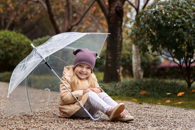 Menina andando em um parque sob um guarda-chuva durante uma chuva