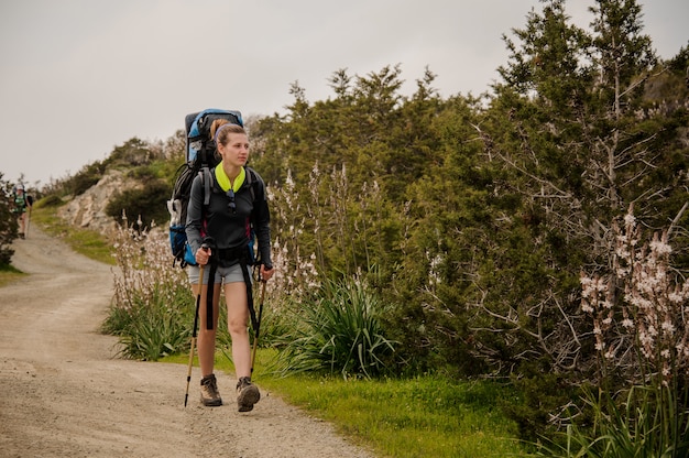 Menina andando no caminho verde com caminhadas mochila e stiks