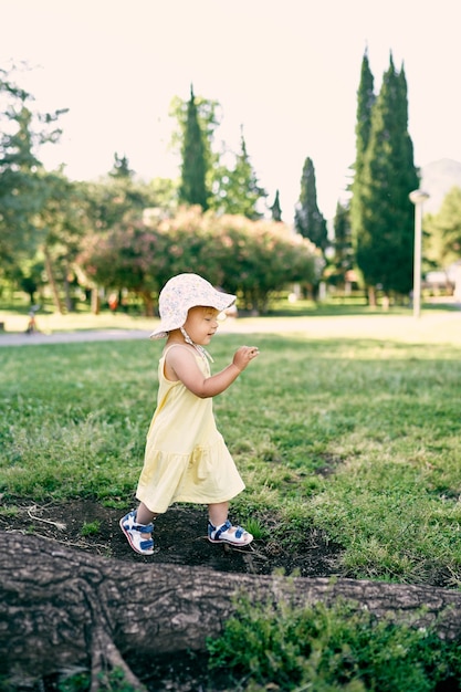 Menina andando no gramado nas raízes de uma árvore