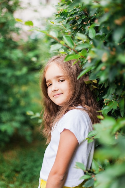 Menina andando no jardim, plantas verdes, arbustos, retrato, vegetação, árvores, verão e primavera, beleza, shorts e camiseta, férias da escola