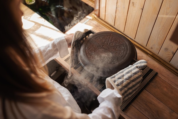 Menina anfitriã tirando panela quente do forno com pão assado