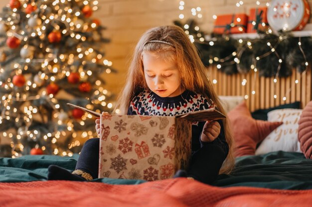 Menina animada abre caixa de presente do papai noel, infância feliz, celebração do feriado, milagre de natal