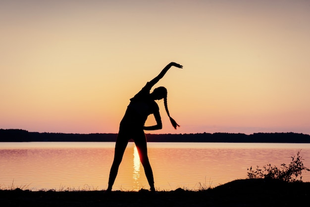 Foto menina ao pôr do sol no lago