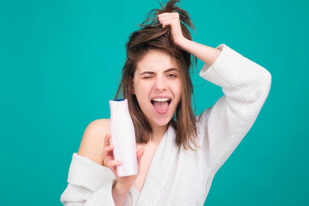 Menina aplicando condicionador de cabelo mulher tocando seu cabelo mulher segura shampoo e condicionador de garrafa