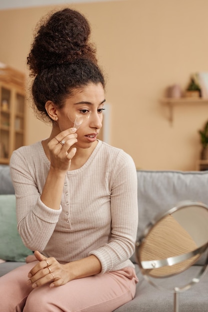 Foto menina aplicando máscara facial e olhando para o espelho