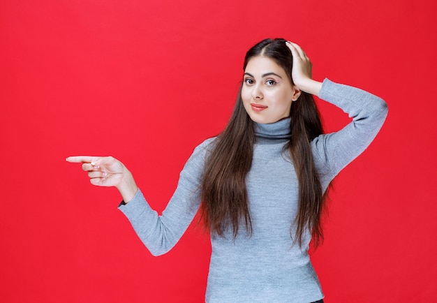 Menina apontando para algo do lado esquerdo.