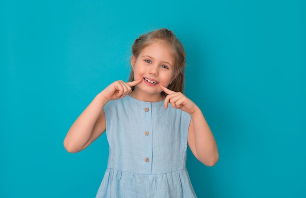 Menina apontando seu sorriso sobre fundo azul