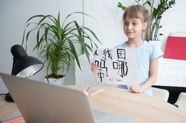 Menina aprendendo chinês enquanto estiver usando seu computador portátil na sala de estar em casa. conceito de atividade familiar.