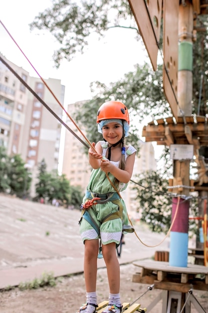 Foto menina, aproveitando o tempo em uma estrutura de corda no parque de aventura