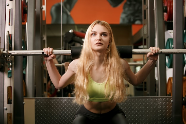 Menina apta que faz lunges com a máquina de ferreiro