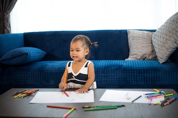 Foto menina ásia, desenho fammily em uma grande folha de papel branco