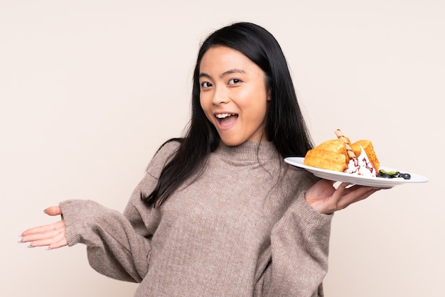 Menina asiática adolescente segurando waffles