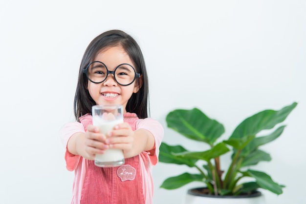 Menina asiática bebe leite com um copo