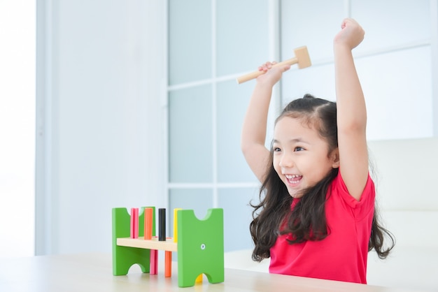 Menina asiática bonita levantando as mãos alegremente enquanto brinca de brinquedo em casa