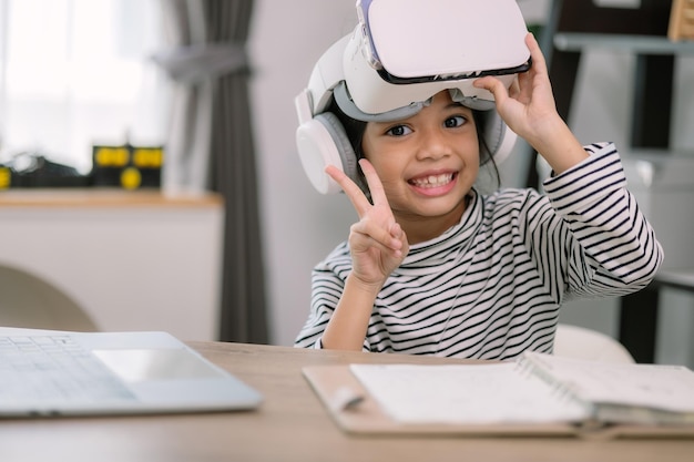 Menina asiática bonita usando óculos VR com um laptop colocado na mesa na aula de tecnologia STEM Educação on-line Erudição