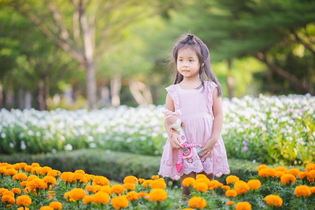 Menina asiática bonitinha com uma boneca no jardim