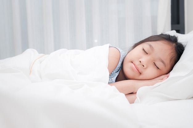 Menina asiática bonitinha dormir na cama no quarto