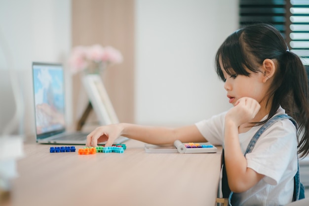 Menina asiática bonitinha se divertindo enquanto brincava com brinquedos ou blocos sentados à mesa