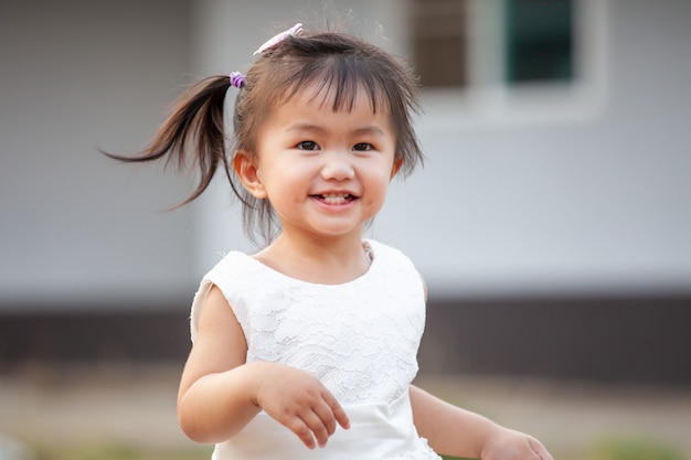 Menina asiática bonitinha sorrindo e correndo com diversão e felicidade