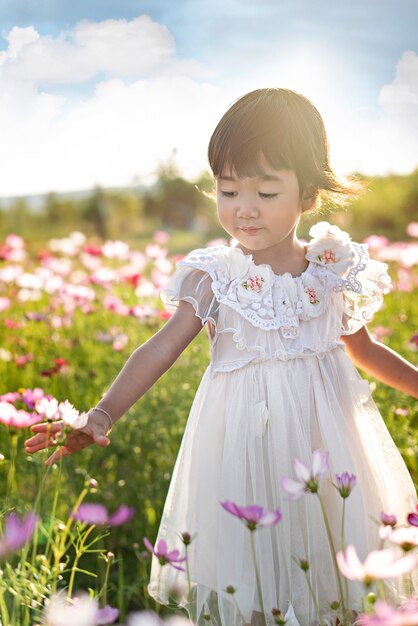 Menina asiática bonito das crianças no campo de flores da natureza