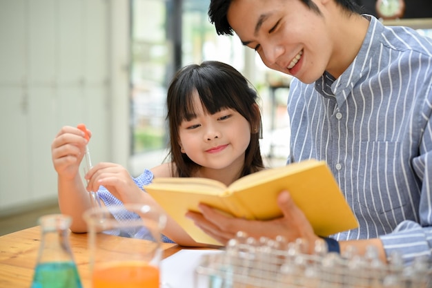 Menina asiática brilhante concentrando-se na aprendizagem de ciências enquanto seu professor explica sobre ciência