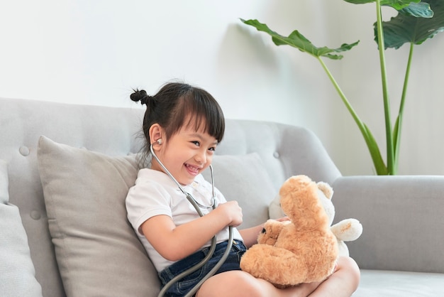 Menina asiática brincando com boneca de brinquedo