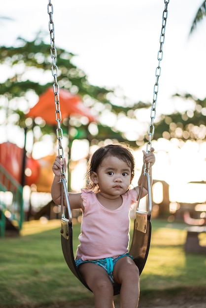 Menina asiática brincando em um balanço e se divertindo no parque