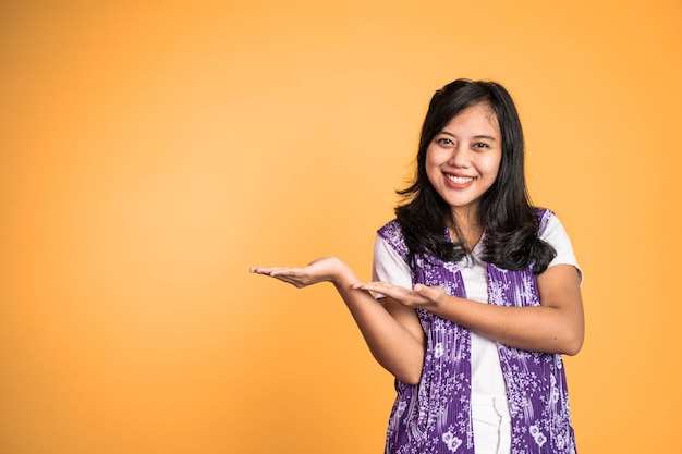 Menina asiática com gesto de mão apresentando algo em fundo isolado