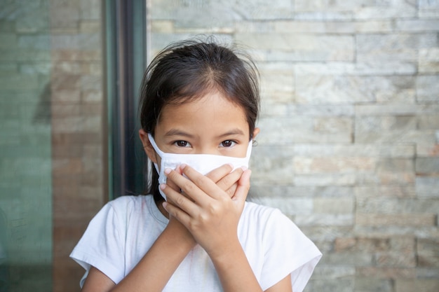 Menina asiática com máscara de proteção para proteger o coronavírus covid-19 e a poluição atmosférica com pm 2.5. anti poluição e vírus. poluição do ar e conceito médico.