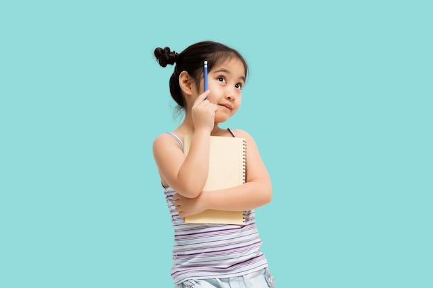 Foto menina asiática com papel e lápis nas mãos olhando para o escritor esperando por musa isolada em fundo verde