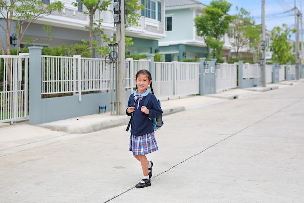 Menina asiática com uniforme escolar e máscara médica andando na rua