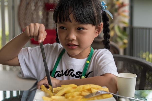 Menina asiática comendo batatas fritas, criança, diversão, batata feliz, fast food