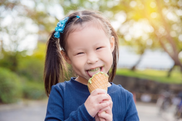 Menina asiática comendo sorvete de chá verde e sorrisos no parque