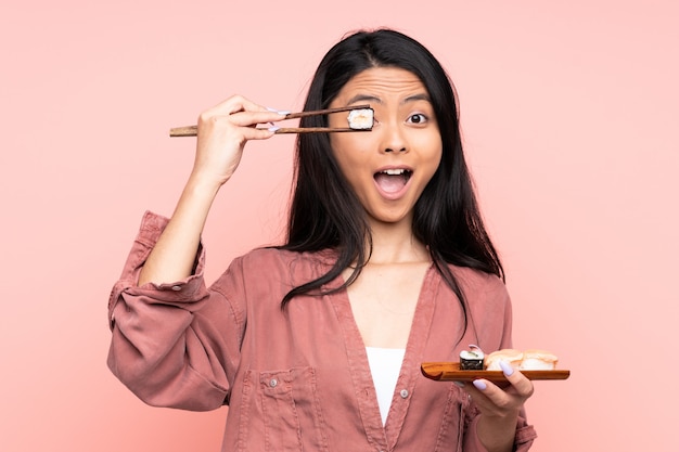 Menina asiática comendo sushi com pauzinhos