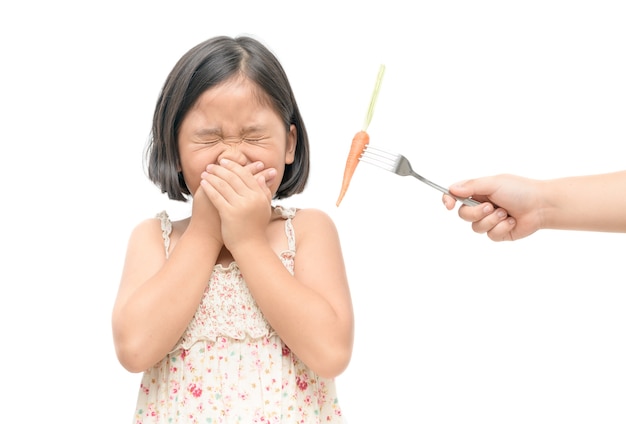 menina asiática criança com expressão de nojo contra vegetais isolado no fundo branco, Refusin