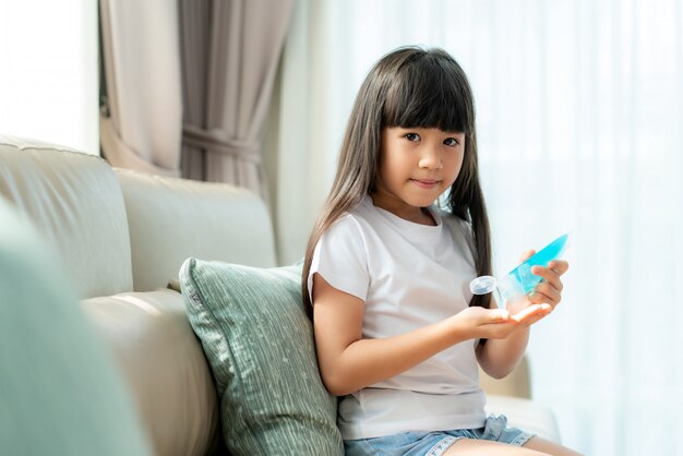 Menina asiática criança usando gel anti-séptico de álcool