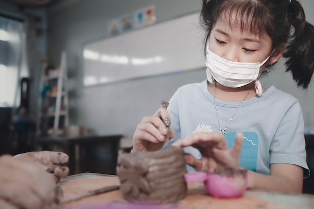 Menina asiática criando tigela de barro em casaEducationhobby e conceito de artesanato