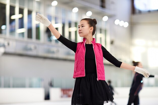 Menina asiática de patinação na pista